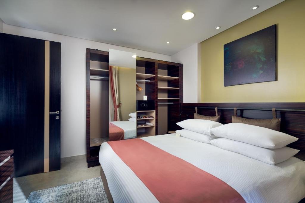 A guest bedroom with a coral runner, dark wood wardrobe and warm lighting