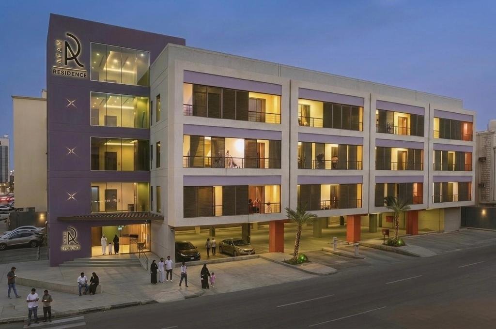 The AFAM Residence building at dusk, with its purple corner tower and lit balconies
