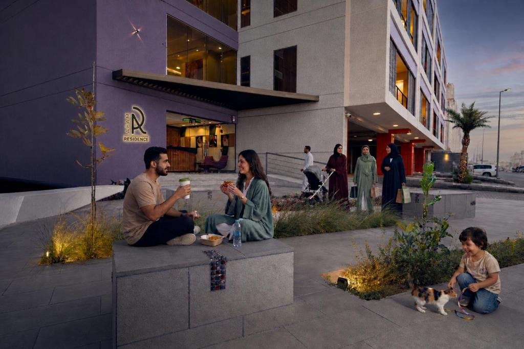 Guests relaxing in the landscaped plaza outside the AFAM Residence entrance at dusk